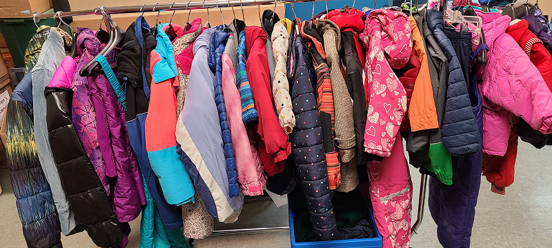 A clothing rack filled with a variety of colorful winter coats in different sizes and styles, hanging closely together indoors.