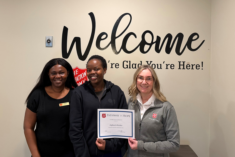 Three people smiling, one holding the certificate of completion for the Pathway of Hope program.