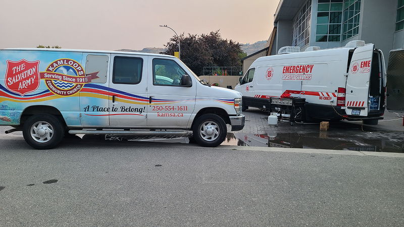 Two Salvation Army Emergency Disaster Services vans parked outdoors, with branding and response signage visible on the sides, positioned near a building.