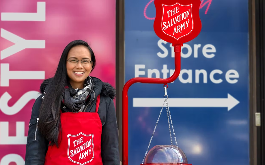 Kettle volunteer in a red Salvation Army apron miling